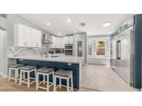 Bright kitchen features white cabinets, mosaic backsplash, stainless appliances and breakfast bar at 6092 S Bridal Vail Dr, Gilbert, AZ 85298