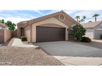 Beautiful home with a two-car garage, desert landscaping, and palm trees in the background at 14566 N 90Th Ln, Peoria, AZ 85381