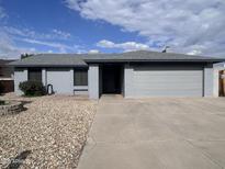 Charming single-story home with gray paint, low-maintenance landscaping, and an attached two-car garage at 10852 N 39Th Ave, Phoenix, AZ 85029