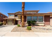 Two-story home featuring a 2-car garage, brick accents, and a well-maintained front yard with desert landscaping at 16022 W Desert Mirage Dr, Surprise, AZ 85379