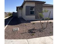 Well maintained single Gathering home featuring a xeriscaped front yard with a small tree, and gray brick accents at 18225 W Larkspur Dr, Goodyear, AZ 85338