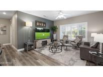 Comfortable living room boasts a ceiling fan, plantation shutters, and entertainment center with fireplace at 16246 W Talara Way, Surprise, AZ 85374