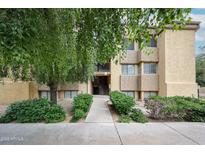 Inviting exterior view of a stucco apartment building entrance with mature trees and manicured landscaping at 18811 N 19Th Ave # 2020, Phoenix, AZ 85027