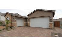 A beautiful home featuring a brick driveway leading to two white garage doors with stone accents on the exterior at 21612 W Pierson St, Buckeye, AZ 85396