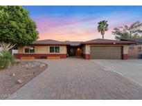 Charming brick home featuring a paved driveway and mature landscaping, under a vibrant sunset sky at 3919 S Siesta Ln, Tempe, AZ 85282