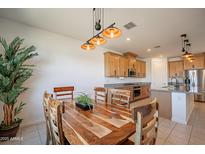 Well-lit dining area with modern lighting, tile floors and views into the kitchen with stainless steel appliances at 4084 E Caitlin Dr, San Tan Valley, AZ 85140