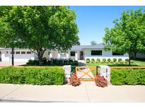 Charming single-story home with a manicured lawn, wood fence, and mature trees in a suburban neighborhood at 4916 E Flower St, Phoenix, AZ 85018