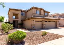 Two story home showcasing a three-car garage, beautiful landscaping, and a charming entrance at 6967 W Potter Dr, Glendale, AZ 85308