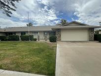 Well-maintained single Gathering house with a green lawn, shrubs, brick accents, and two car garage at 15438 N Lakeforest Dr, Sun City, AZ 85351