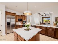 Bright kitchen boasts stainless appliances, white countertops, wood cabinets, and island, with an open view to the living room at 10934 E La Verna Way, Scottsdale, AZ 85262