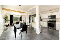 Open concept living spaces flow together, featuring black dining set, neutral sofa and a crisp, white kitchen with subway tile at 2542 W Missouri Ave, Phoenix, AZ 85017