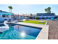 Inviting pool area featuring lounge chairs, patio dining, and artificial turf cornhole in a beautifully landscaped backyard at 8444 E Piccadilly Rd, Scottsdale, AZ 85251