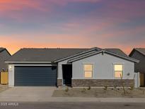 Charming single-story home with gray stucco, stone accents, desert landscaping, and a two-car garage at 8634 W Albeniz Pl, Tolleson, AZ 85353