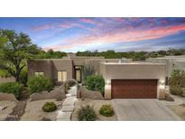 A lovely single-story home featuring a stucco exterior, desert landscaping, and a cozy two-car garage at dusk at 11366 E White Feather Ln, Scottsdale, AZ 85262