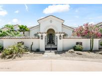 Elegant gated front entrance with desert landscaping and a charming, arched entryway leads to the home's front door at 7003 E Avenida El Alba --, Paradise Valley, AZ 85253
