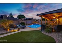 Relaxing backyard featuring a private pool, covered patio, lush lawn, and comfortable lounge furniture at 4338 W Creedance Blvd, Glendale, AZ 85310