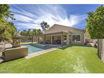 Inviting backyard featuring a covered patio, pool, and well-manicured artificial grass at 6264 E Omega St, Mesa, AZ 85215