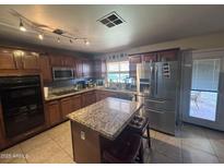 Spacious kitchen with stainless steel appliances, granite countertops, and ample cabinet space for storage at 7141 W Denton Ln, Glendale, AZ 85303