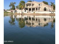 Waterfront home with two-story architecture, balcony, lush palms, and a calm lake view at 1414 N Palmsprings Dr, Gilbert, AZ 85234