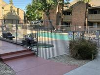 Fenced community pool with clear water, lounge chairs, and grassy area surrounded by residences at 200 E Southern Ave # 133, Tempe, AZ 85282