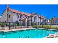 Community pool with lush landscaping and a view of the building's exterior, under a clear, sunny sky at 6262 E Brown Rd # 65, Mesa, AZ 85205