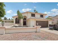 Inviting two-story home featuring a well-maintained lawn, desert landscape, and an attached two-car garage at 11021 N 64Th Ln, Glendale, AZ 85304