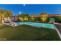 Beautiful backyard with a sparkling pool, lounge area, and lush landscaping, perfect for outdoor entertaining at 11705 W Luxton Ln, Avondale, AZ 85323