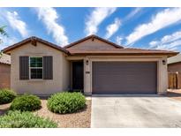 Charming single story home with a two car garage, low maintenance landscaping, and shuttered window accents at 5750 S 250Th Dr, Buckeye, AZ 85326