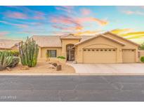 Charming beige home featuring a three-car garage, desert landscaping, and a tiled roof under a beautiful sunset at 14999 W Mulberry Dr, Goodyear, AZ 85395