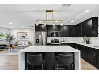 Modern kitchen boasts sleek black cabinets, a white quartz countertop island and stainless appliances at 7149 E Jensen St, Mesa, AZ 85207