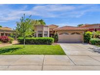 Charming home with tile roof, landscaped front yard, and attached two car garage on a sunny day at 10591 E Saddlehorn Dr, Scottsdale, AZ 85258