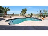 Relaxing backyard pool with custom stone waterfall feature and lush desert landscaping with golf course view at 13458 W Coronado Rd, Goodyear, AZ 85395