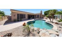 Inviting backyard with a sparkling pool, rock features, and desert landscaping at 13458 W Coronado Rd, Goodyear, AZ 85395