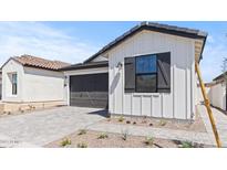 Charming home featuring white siding, a dark gray garage door and meticulous landscaping at 20308 W Roma Ave, Buckeye, AZ 85396