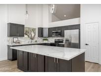 Modern kitchen featuring an island with a white countertop and dark cabinets plus stainless steel appliances at 3022 E Emile Zola Ave, Phoenix, AZ 85032