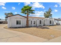 Charming single-story home with desert landscaping, white stucco, arched porch and mature palm tree at 5127 W Willow Ave, Glendale, AZ 85304