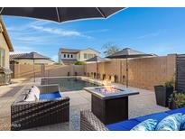 Backyard oasis with a sparkling pool, comfortable seating around a modern fire pit, and privacy fencing at 26232 N 121St Ln, Peoria, AZ 85383