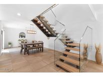 Modern staircase with wood treads and glass railing leads to upper level, adjacent dining area with seating at 309 E Huntington Dr, Tempe, AZ 85282