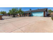 Charming single-story home featuring a light blue garage door and a wide driveway at 4402 N 79Th Dr, Phoenix, AZ 85033