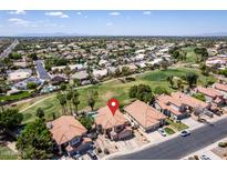 Expansive aerial view of a community with lush golf courses and houses with red tiled roofs under a clear, blue sky at 5953 W Aurora Dr, Glendale, AZ 85308