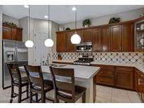 Gourmet kitchen features stainless steel appliances, a white quartz island, and dark wood cabinets at 6694 S Banning St, Gilbert, AZ 85298