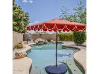 Backyard pool area featuring rock waterfall, basketball hoop, and red umbrella at 720 W Gail Ct, Gilbert, AZ 85233