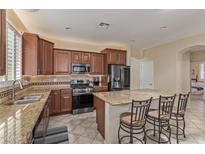 This kitchen features a granite island with seating, stainless steel appliances, and dark wood cabinets at 81 E Rock Wren Dr, San Tan Valley, AZ 85143