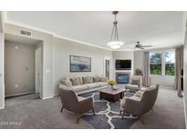 Bright living room features a fireplace, ceiling fan, and large picture window at 19777 N 76Th St # 3238, Scottsdale, AZ 85255