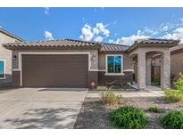 Charming home exterior featuring a well-maintained yard, two-car garage, and covered entryway at 19875 W Badgett Ln, Litchfield Park, AZ 85340