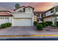 Charming home featuring a two-car garage, desert landscaping, and a Spanish tile roof at sunset at 11011 N 92Nd St # 1010, Scottsdale, AZ 85260