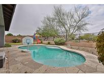 Backyard pool features stone patio, basketball hoop, and privacy wall in outdoor living space at 16140 W Sierra St, Surprise, AZ 85379