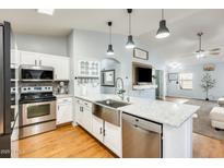 Modern kitchen featuring a spacious island with a stainless steel sink and appliances, and white cabinets at 11822 W Softwind Dr, Sun City, AZ 85373