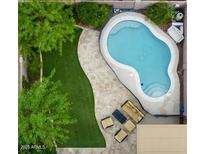 Aerial view of a backyard oasis featuring a freeform pool, lush greenery, and a cozy seating area at 4712 E Amberwood Dr, Phoenix, AZ 85048