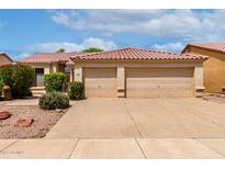 Charming home featuring a tile roof and a spacious three-car garage, complemented by lush landscaping at 9154 E Caribbean Ln, Scottsdale, AZ 85260